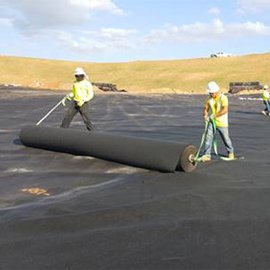 Two men unrolling mirafi non-woven geotextile