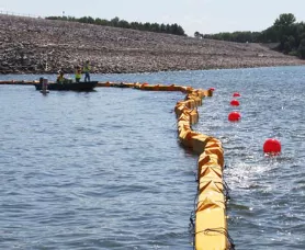 silt curtain on rough water with workers installing yellow barrier